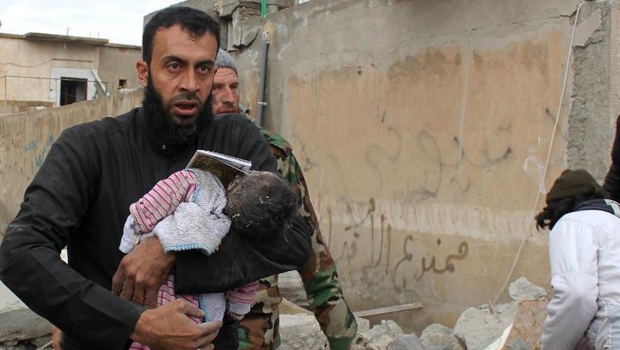 Un Syrien porte le corps d'un bébé mort après des frappes aériennes à Raga le 27 novembre 2014