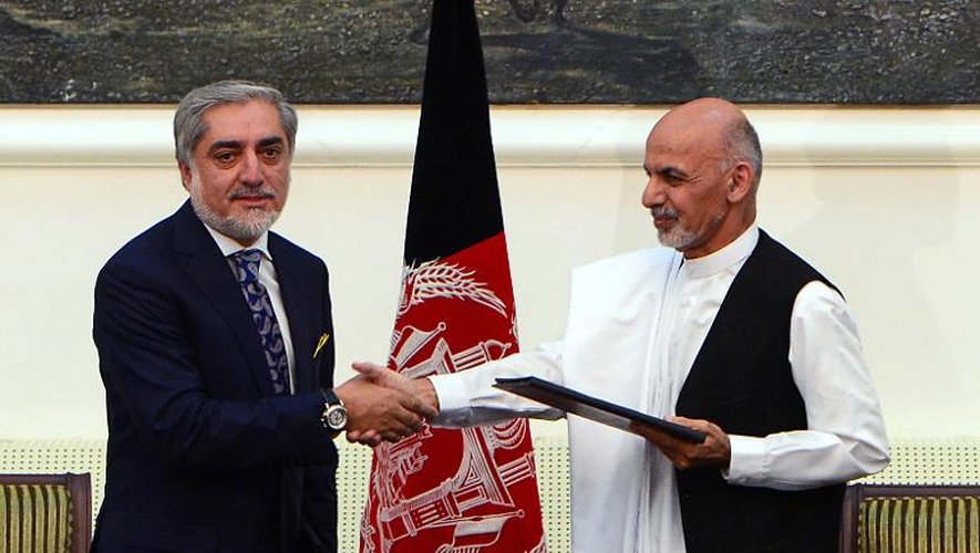 Abdullah Abdullah (G) et Ashraf Ghani se serrent la main le 21 septembre 2014 à Kaboul après s'être mis d'accord sur un gouvernement d'union nationale