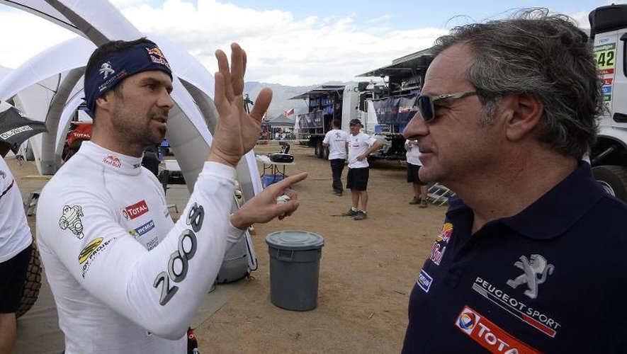 Le pilote espagnol Carlos Sainz (d) en pleine discussion avec son coéquipier chez Peugeot, le Français Cyril Despres, à la fin de la 3e étape à Chilecito, le 6 janvier 2015