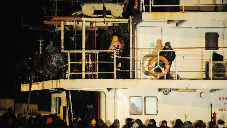Des refugiés syriens attendent de débarquer au port italien de Gallipoli, le 31 décembre 2014. Leur bateau, le Blue Sky M, a été secouru par les gardes-côtes italiens, après avoir été abandonné avec quelque 800 personnes à bord par les passeurs