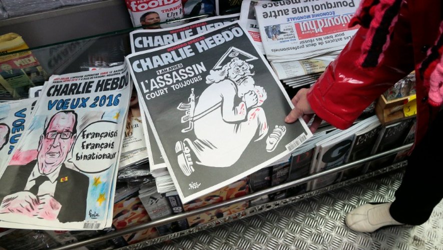 Une femme regarde dans un kiosque, le 6 janvier 2016 à Paris, le numéro spécial de Charlie Hebdo  paru un an après l'attentat