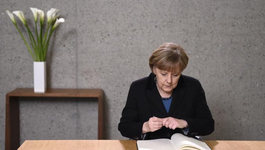 La chancelière allemande Angela Merkel à l'Ambassade de France à Berlin écrit sur le registre de condoléances ouvert pour les victimes de l'attaque de Charlie Hebdo, le 8 janvier 2015