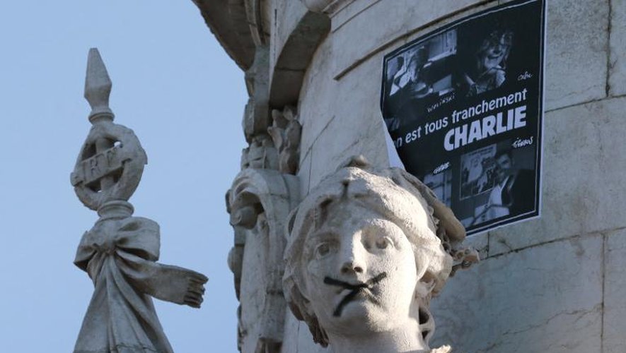 Une croix noire barre la bouche de la statue de Marianne, le 11 janvier 2015 sur la place de la République à Paris, départ de la marche contre les attaques terroristes de cette semaine