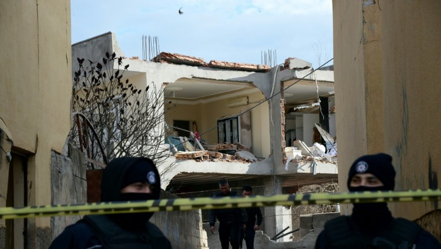Des policiers turcs devant un bâtiment détruit après une attaque à la voiture piégée, le 14 janvier 2016 à Cinar, dans le sud-est du pays