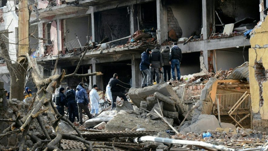 Des policiers turcs devant un bâtiment détruit par l'explosion d'une voiture piégée contre un commissariat, le 14 janvier 2016 à Cinar, dans le sud-est