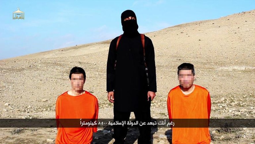 Capture d'écran d'une vidéo diffusée le 20 janvier 2015 par le média du groupe Etat islamique Al-Furqan montrant un membre de l'EI près de deux otages japonais dans un endroit non localisé