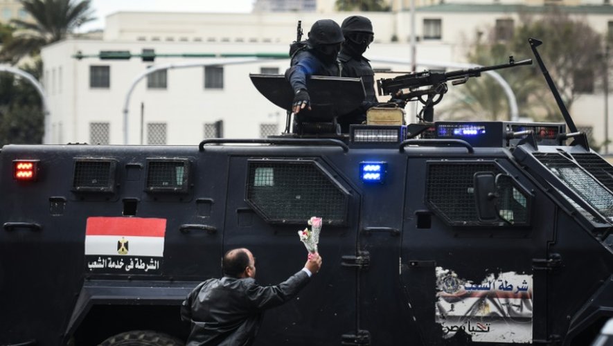 Un Egyptien tend des fleurs à des policiers des forces spéciales, sur la place Tahrir, au Caire, le 25 janvier 2016