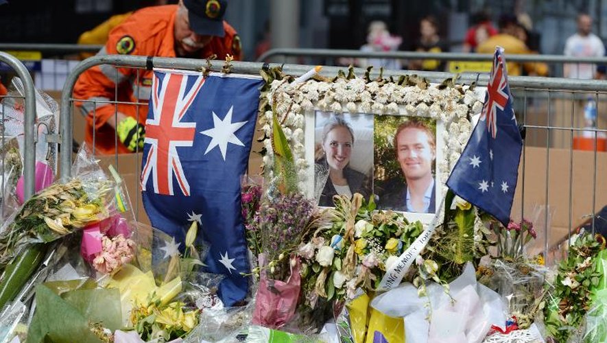 Portraits de Katrina Dawson (g) et Tori Johnson, tués lors de la prise d'otages dans un café à Sydney, au milieu de fleurs sur le site en hommage aux victimes, à Sydney, le 23 décembre 2014
