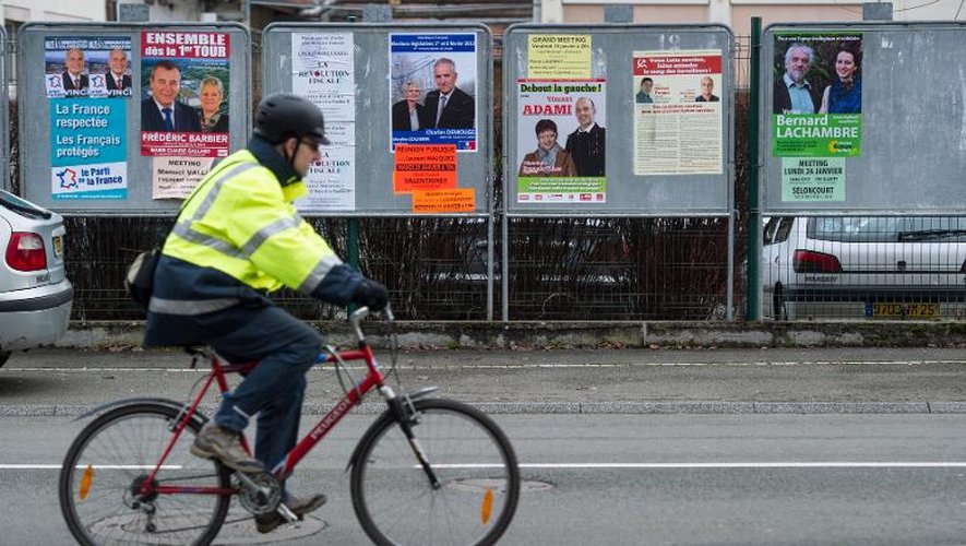 Un cycliste passe devant des affiches électorales pour les législatives partielles dans le Doubs, le 21 janvier 2015 à Hérimoncourt