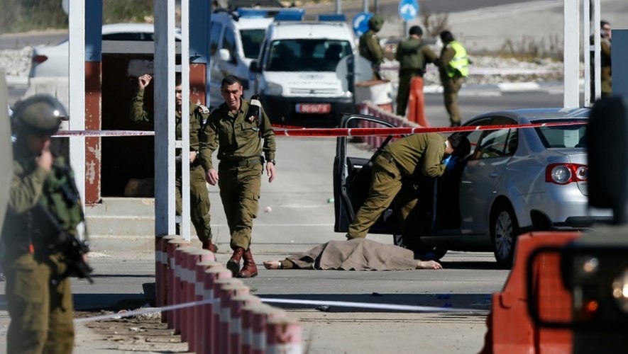 Des soldats israéliens près du corps d'un palestinien tué après avoir attaqué des Israéliens, à Beit El, le 31 janvier 2016
