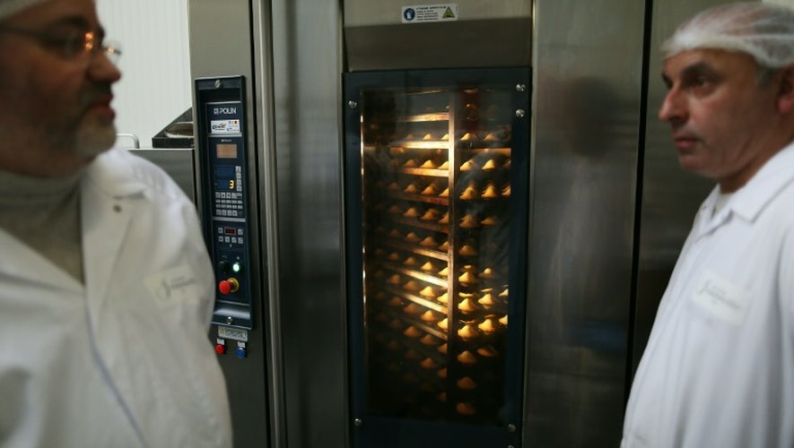 Le propriétaire de la biscuiterie Jeannette George Viana (g) devant un four qui cuit des madeleines dans l'unité de production, à Demouville près de Caen le 26 janvier 2016