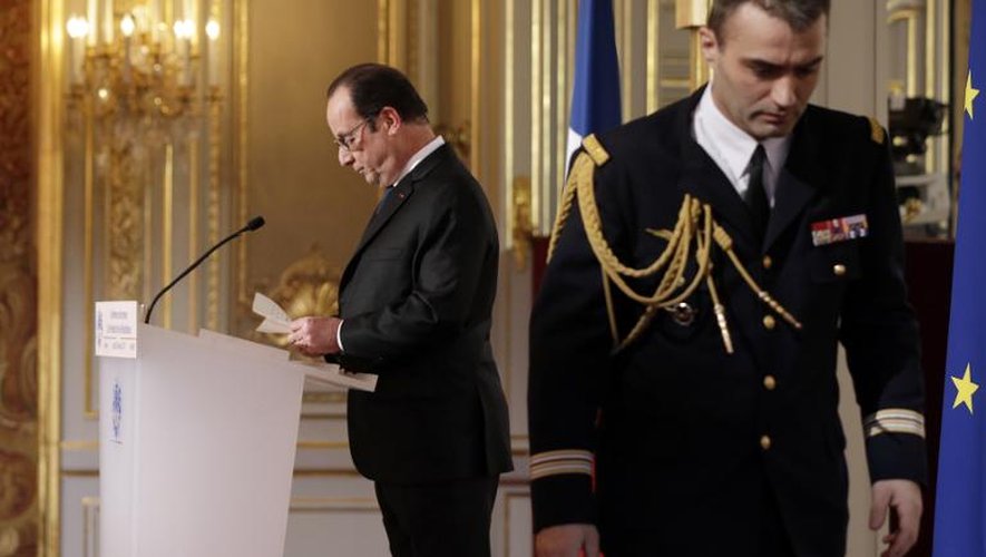 Le président Francois Hollande lit une note que lui apportée son aide de camp, pendant sa conférence de presse le 5 février 2015 à l'Elysée à Paris