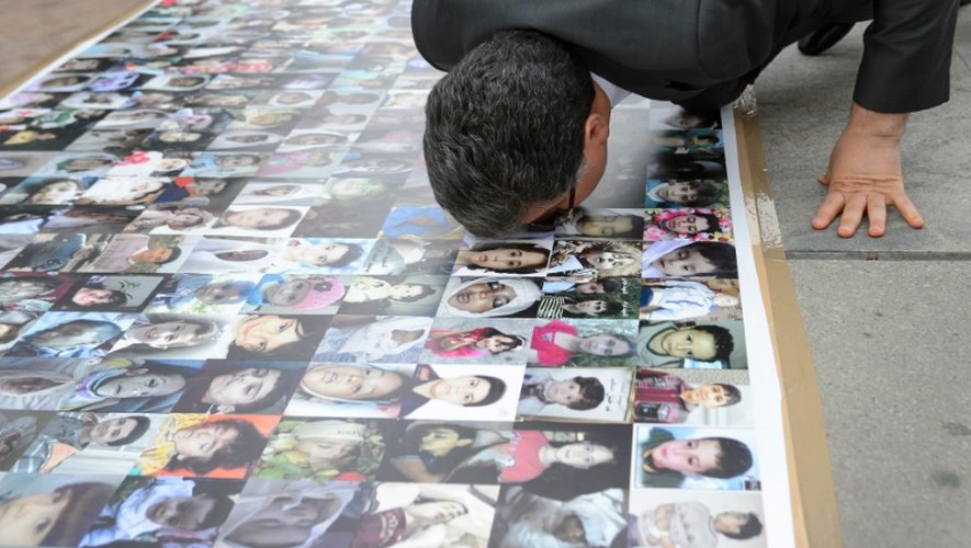 Le représentant du HCN, Salem al-Meslet, s'agenouille sur le sol tapissé de photos insoutenables d'enfants syriens tués dans des bombardements ou disparus, le 2 février 2016 à Genève