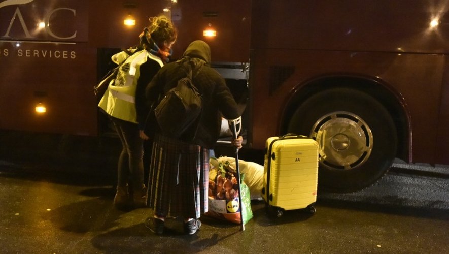 Une femme aidée par une bénévole lors de l'évacuation d'un campement de Roms le 3 février 2016 dans le nord de Paris