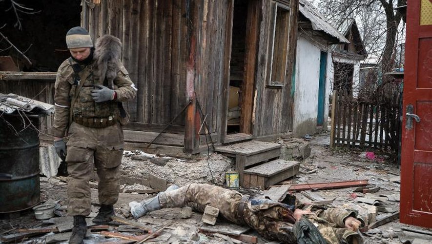 Un rebelle prorusse, un chat sur les épaules, passe devant le corps d'un soldat ukrainien le 7 février 2015 à  Vuglegirsk dans l'est de l'Ukraine