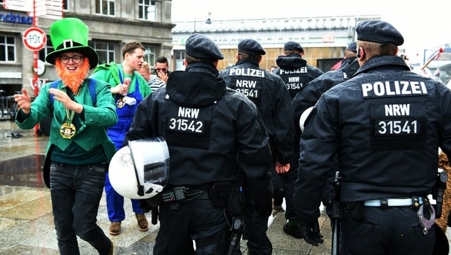 Un festivalier déguisé en bouffon fête le début du carnaval de Cologne, en Allemagne, près de policiers, le 4 février 2016
