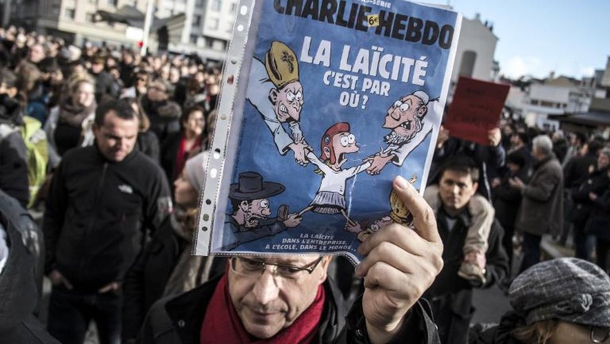 Un homme tient une couverture de Charlie Hebdo sur la laïcité lors d'une manifestation le 11 janvier 2015 à Lyon