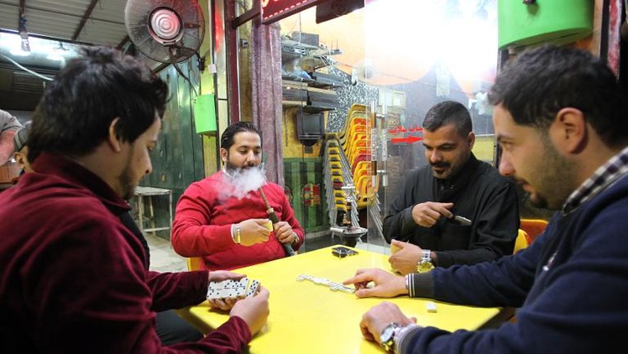 Des hommes jouent au domino en fumant des cigarettes à la terrasse d'un café le 8 février 2015 à Bagdad