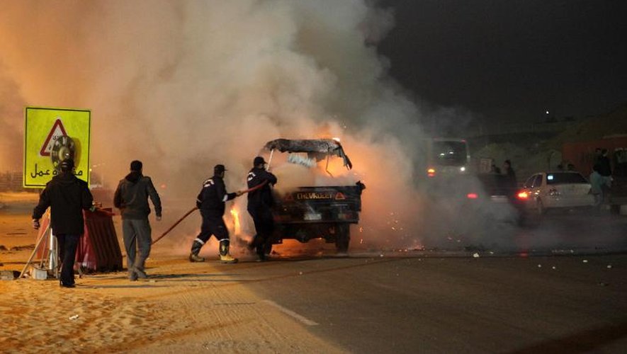 Des pompiers égyptiens autour d'un véhicule incendié lors de heurts entre la police et des supporteurs de foot au Caire le 8 février 2015