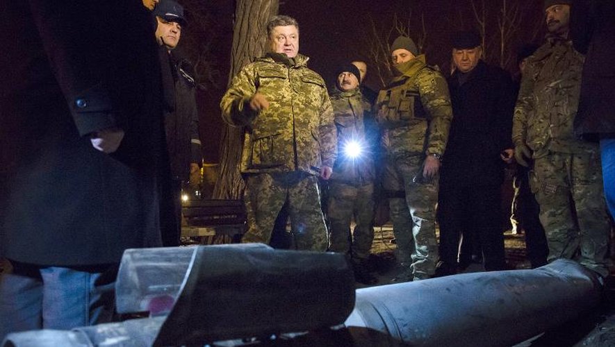 Le président ukrainien Petro Porochenko (c) regarde une roquette non explosée, le 10 février 2015 à Kramatorsk, dans la région de Donetsk, dans l'Est du pays