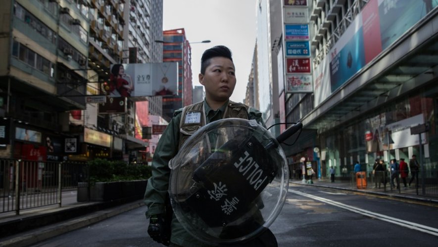 Une femme de la police anti-émeutes de Hong Kong le 9 février 2016 devant une rue interdite d'accès après les heurts de la nuit entre la police et des protestataires dans le quartier de Mongkok à Hong Kong le 9 février 2016
