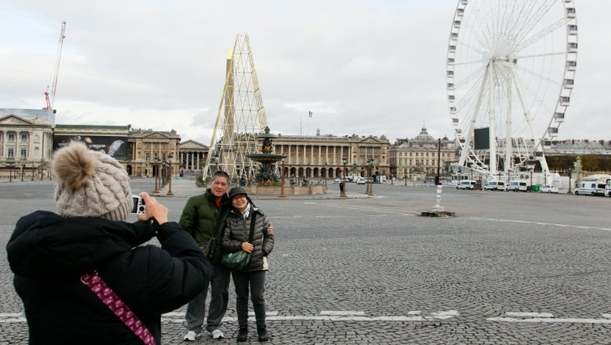 Des touristes prennent la pose devant la place de la Concorde à Paris le 30 novembre 2015