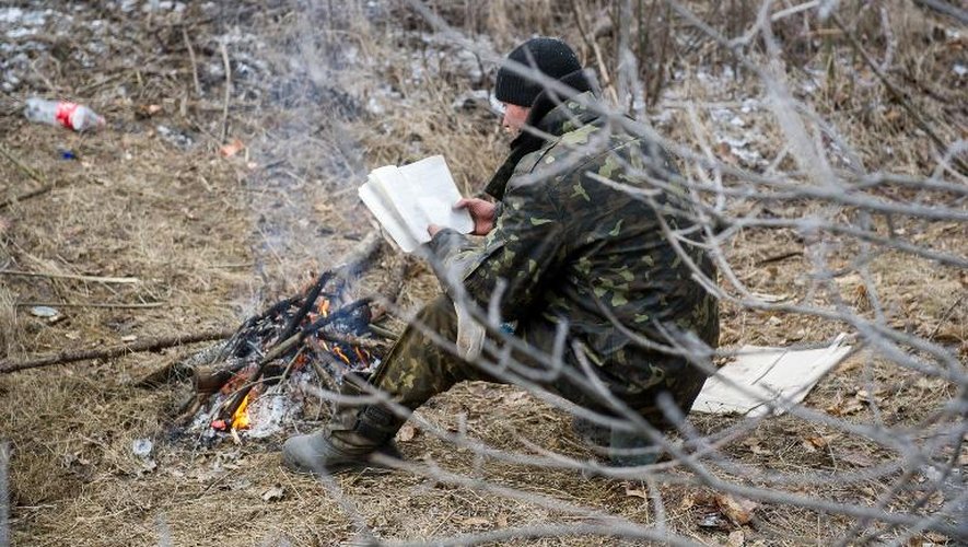 Un soldat ukrainien lit un livre devant un feu de camp à Svitlodarsk près de Debaltseve le 15 février 2015