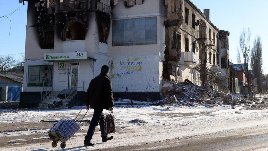 Un homme passe le 18 février 2015 devant un immeuble de la ville de Uglegorsk, près de Debaltseve, dans la la région de Donetsk