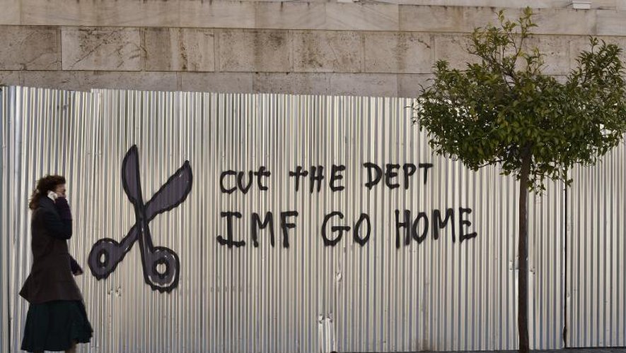 Une femme passe devant un graffiti réclamant la réduction de la dette et le retrait du FMI, le 20 février 2015 dans le centre d'Athènes