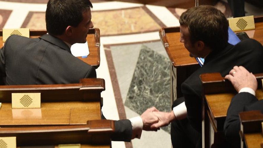 Poignée de mains entre le Premier ministre Manuel Valls et le ministre de l'Economie Emmanuel Macron le 19 février 2015 à l'Assemblée nationale à Paris