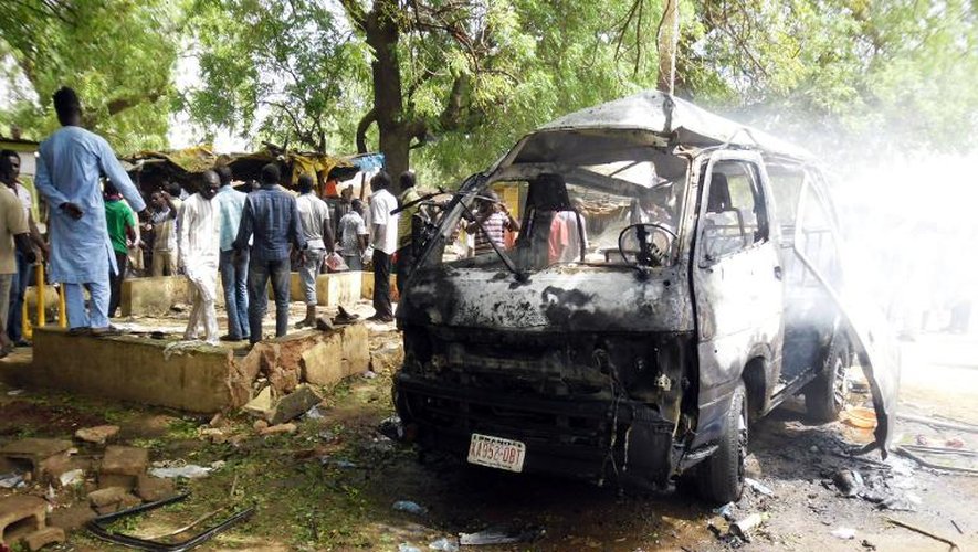 Des habitants se tiennent à côté d'un minibus visé par un attentat-suicide le 24 février 2015 à Potiskum, dans le nord-est du Nigeria
