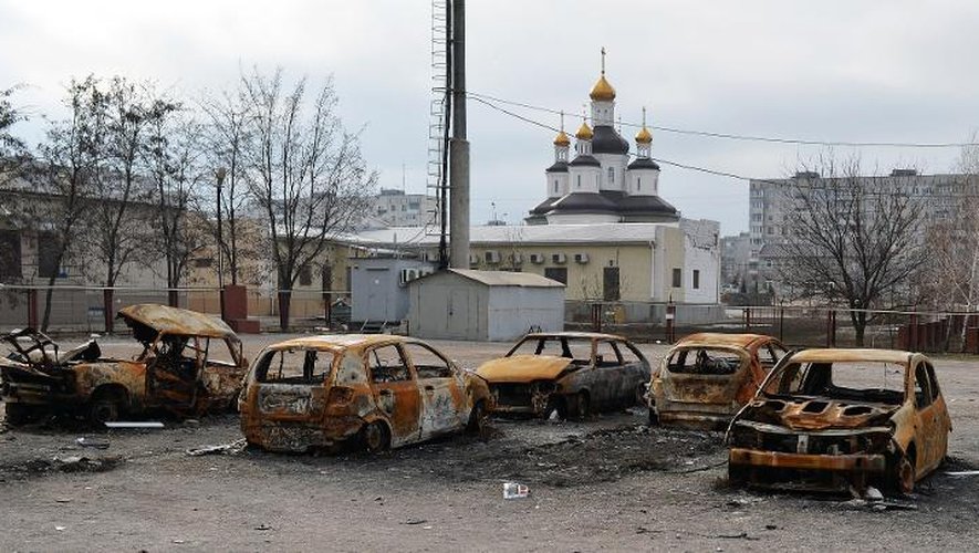 Des voitures détruites après un bombardement près d'une église à Marioupol le 25 février 2015