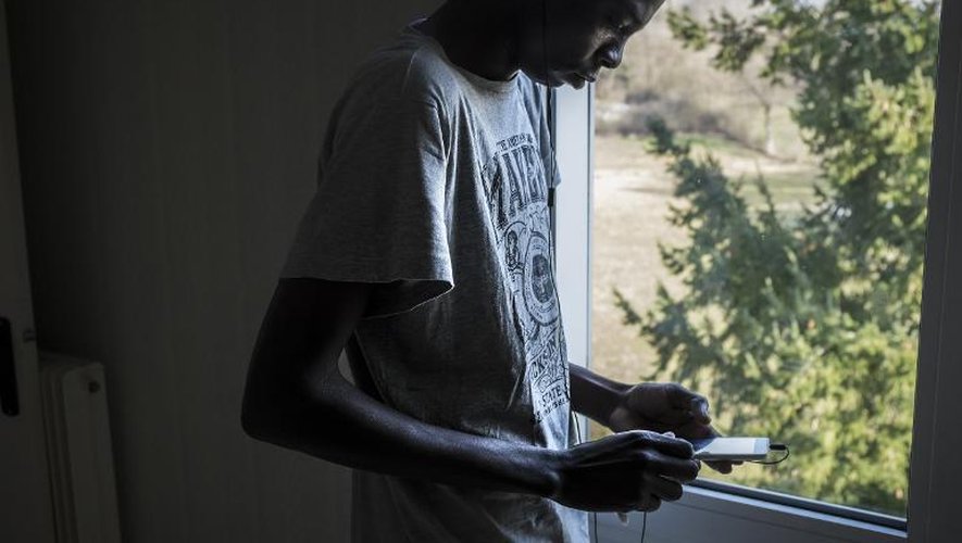 Un immigrant soudanais regarde son téléphone dans sa chambre d'une ancienne caserne de gendarmerie transformée en centre d'accueil pour migrants, le 13 février 2015