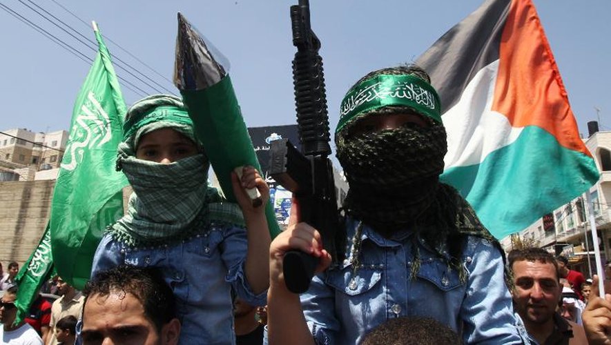 Des enfants palestiniens brandissent des armes en plastique et portent des foulards aux symboles du Hamas lors d'une manifestation à Hébron le 15 août 2014