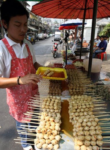 Un vendeur de rue thaïlandais devant son étal dans une rue de Bangkok, le 10 février 2007