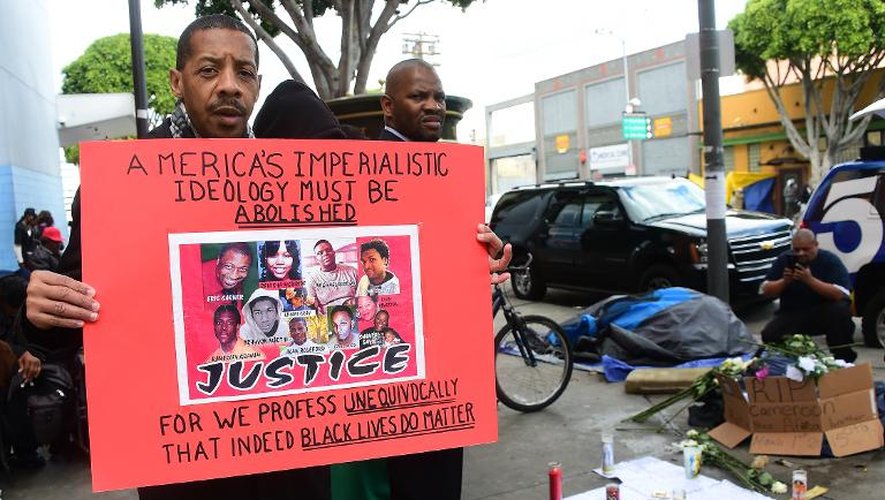 Un homme tient une pancarte sur laquelle est écrit que l'"Impérialisme américain doit être aboli" devant un mémorial en hommage à un sans-abri tué par balle par la police de Los Angeles, le 2 mars 2015