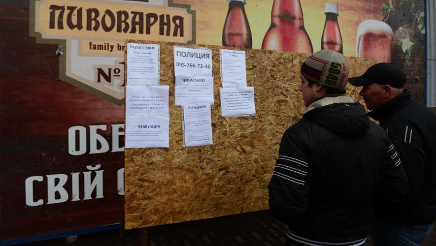 Des personnes consultent des annonces, le 2 mars 2015, affichées place Lénine à Debaltseve en Ukraine