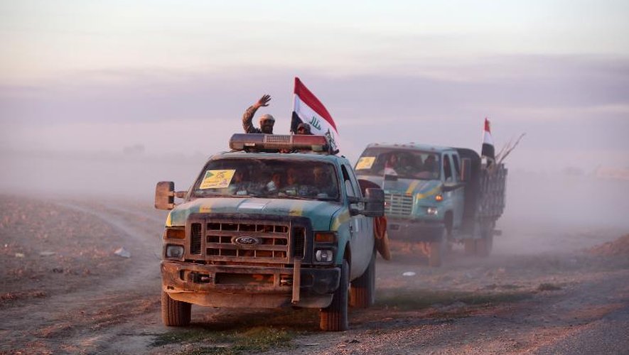 Des membres chiites des forces gouvernementales brandissent le drapeau irakien à Ad-Dawr le 6 mars 2015 lors d'une opération destinée à reprendre Tikrit tombée sous le joug de l'Etat islamique