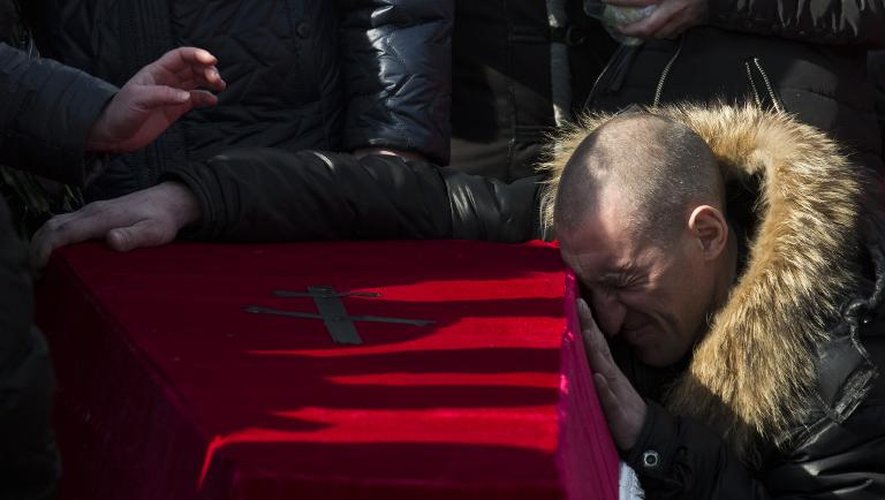 Le parent d'un mineur victime d'un coup de grisou se recueille le 6 mars 2015 sur son cercueil lors de ses funérailles dans un cimetière de Donetsk, à l'est de l'Ukraine