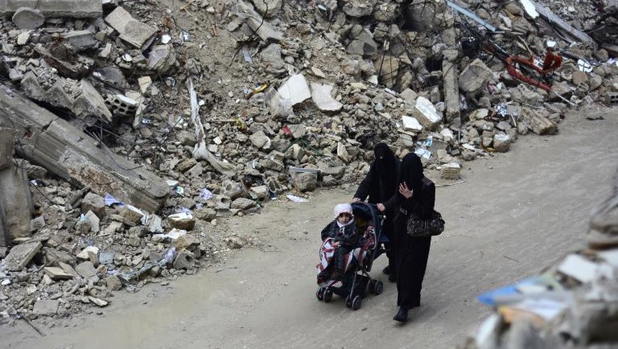 Des femmes traversent les ruines de Douma (Syrie) avec une poussette le 13 février 2015