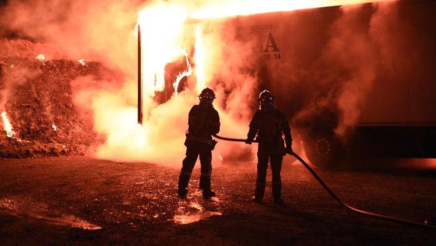 Des pompiers éteignent un incendie provoqué par des producteurs de porcs français qui ont mis le feu à une remorque d'un camion espagnol transportant de la viande en provenance de ce pays, le 8 mars 2015 à Landivisiau, dans le Finistère
