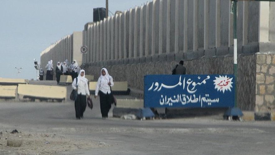 De jeunes Egyptiennes passent devant une pancarte stipulant "Interdiction de passer sous peine de tirs" à Al-Arish dans le Sinaï, le 17 novembre 2014