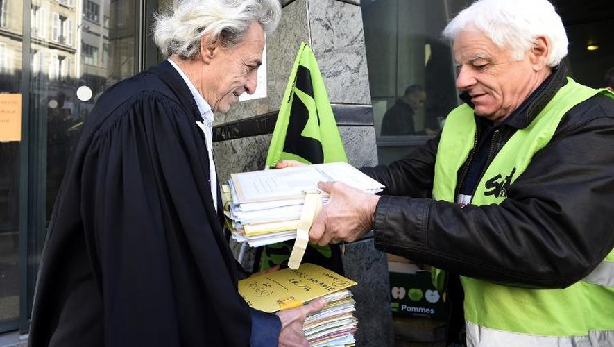 Un cheminot du syndicat SUD-rail tend un dossier à l'avocat des salariés, Xavier Robin (D) devant le Conseil des prud'hommes de Paris, le 12 mars 2015