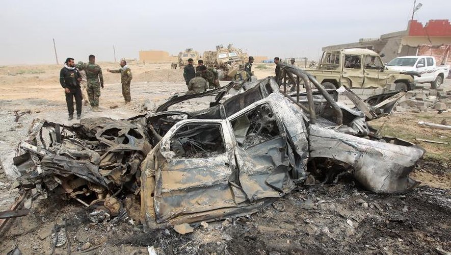 Des soldats irakiens le 12 mars 2015 devant des véhicules détruits près de Tikrit