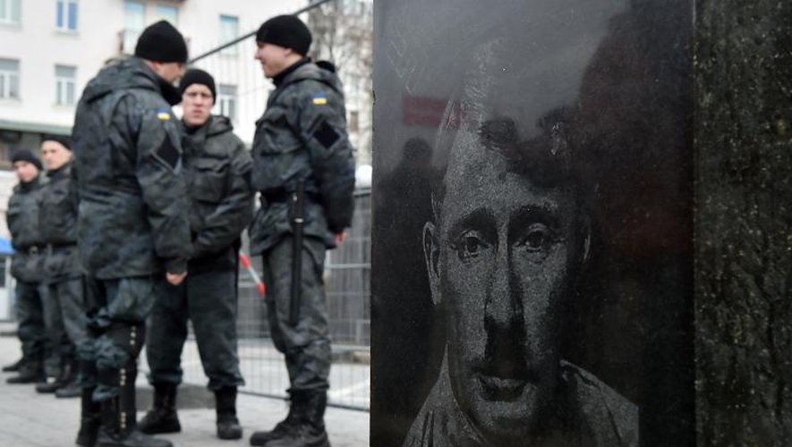 Des policiers près d'une sculpture montrant le président russe Vladimir Poutine avec une moustache rappelant Adolf Hitler, le 15 mars 2015 à Kiev