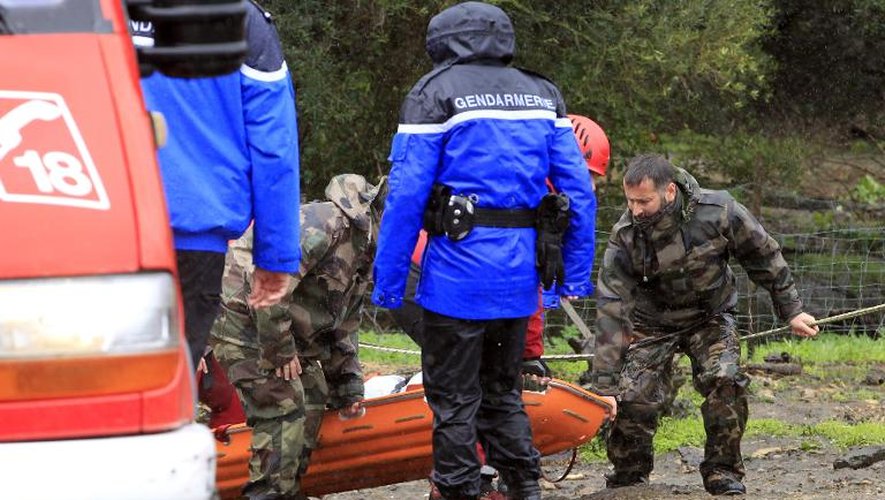 Gendarmes et pompiers évacuent le corps d'une personne qui a péri dans le inondations près du village d'Oletta le 17 mars 2015