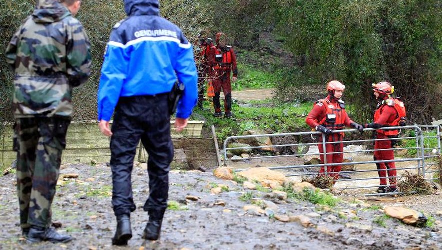 Gendarmes et pompiers attendent pour évacuer le corps d'une personne qui a péri dans le inondations près du village d'Oletta le 17 mars 2015