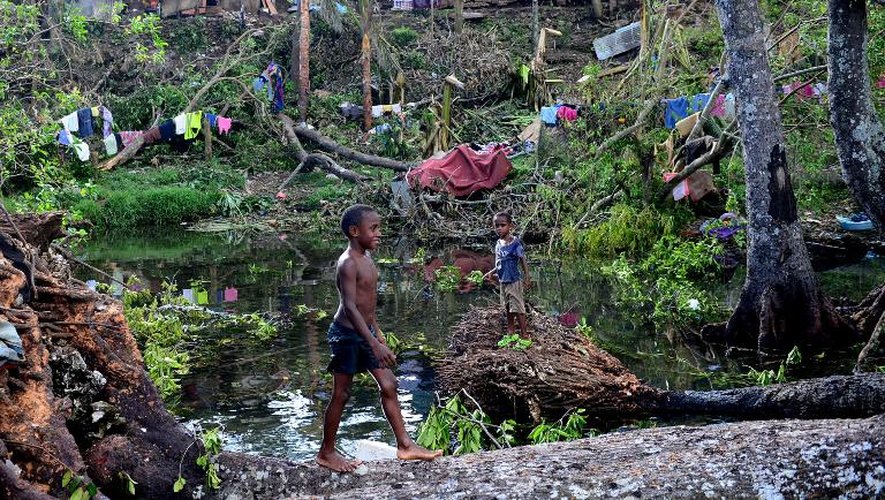 Des enfants jouent dans l'eau au milieu de débris d'arbres déracinés par le cyclone Pam, le 17 mars 2015 à Port-Vila, au Vanuatu