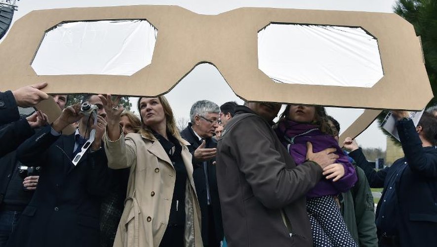 Des personnes regardent l'éclipse partielle solaire au travers de lunettes de protection géantes, le 20 mars 2015, à la Cité de l'Espace à Toulouse
