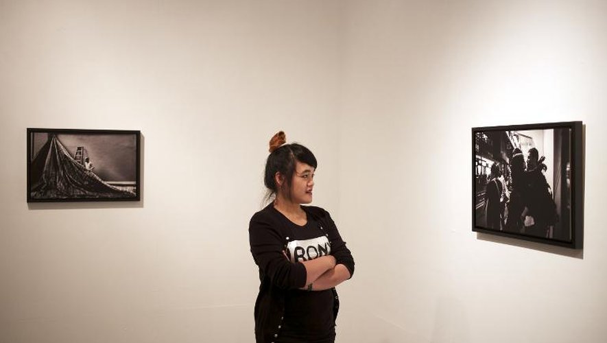 Xyza Cruz Bacani, en train de regarder l'exposition de ses clichés le 21 mars 2015 à Macao, a découvert son talent grâce à son employeur qui lui a prêté il y a quatre ans de quoi acquérir son premier boîtier, un Nikon D90